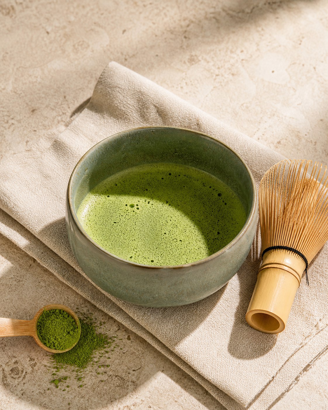 Whisked Kai matcha in a sage ceramic bowl with bamboo tea tools